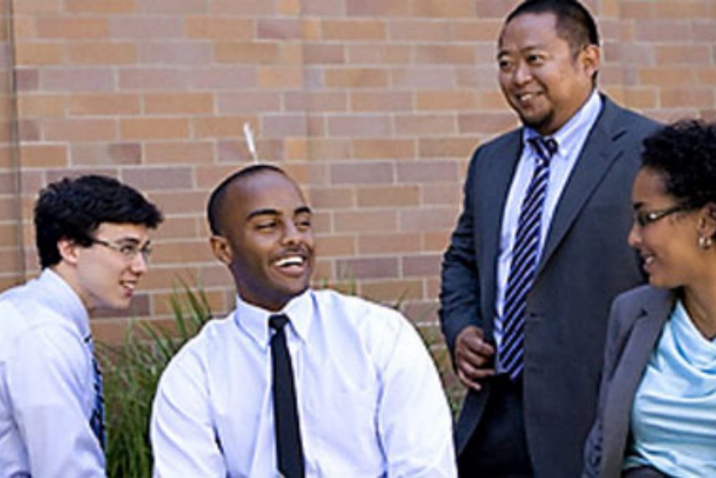 Five Competitive Edge participants smile in front of a brick wall