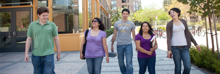 A group of fours students walking on campus and laughing